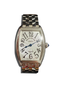 Montre vintage de luxe à boîtier tonneau poli, cadran argenté guilloché avec grands chiffres stylisés, bracelet métal et cabochon bleu sur la couronne ; Valais, Suisse.