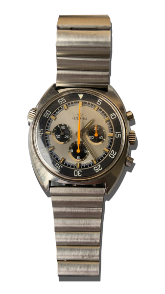 Montre vintage de luxe type chronographe en acier avec bracelet métal, cadran gris à trois compteurs, lunette noire graduée et détails orange ; Valais, Suisse.