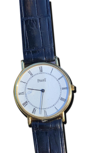 Montre vintage de luxe au style classique : boîtier doré fin, cadran blanc à chiffres romains et bracelet en cuir noir embossé ; Suisse, Valais, achat antiquaire