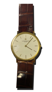 Montre vintage de luxe au style classique : boîtier doré fin, cadran clair épuré avec index bâtons, bracelet cuir brun façon crocodile