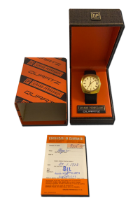Montre de collection quartz au boîtier doré, cadran clair et bracelet noir, avec écrin d’origine orange/noir et certificat de garantie