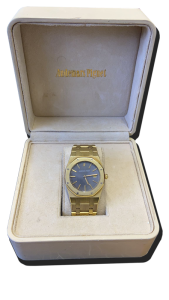 Montre de collection en métal doré avec bracelet intégré, cadran bleu texturé et lunette octogonale, présentée dans un écrin – achat et estimations montres