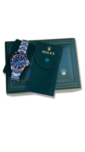 Montre de collection style plongée sur bracelet acier, cadran noir avec date (loupe), lunette tournante, posée sur écrin vert