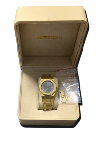 Montre de collection en métal doré, cadran bleu et bracelet intégré, présentée dans son écrin avec maillons supplémentaires